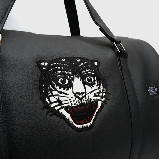 Close-up of embroidered tiger patch on black travel duffle bag