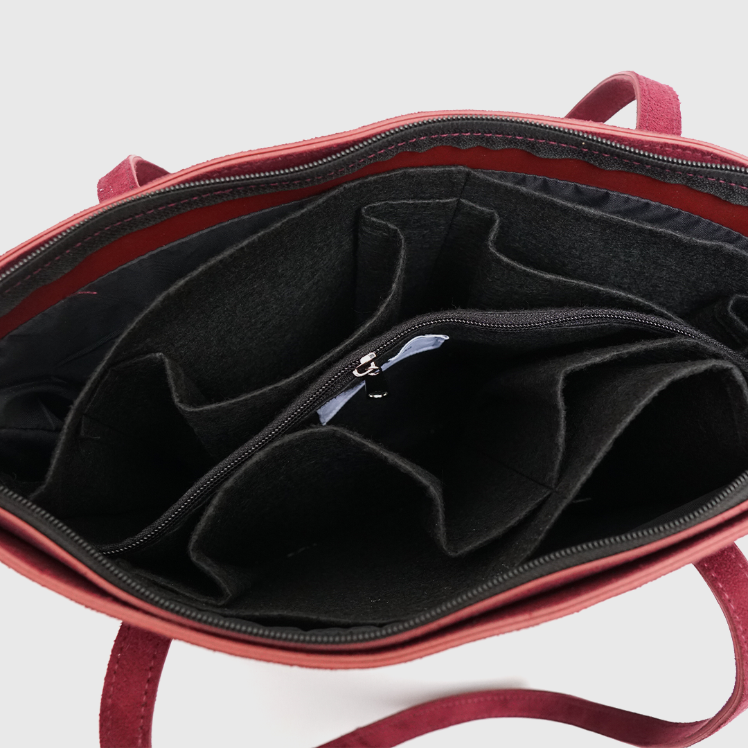 Woman holding stylish maroon suede tote bag